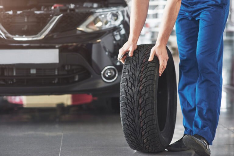 technician with blue workwear holding wrench tire while showing thumb up 2